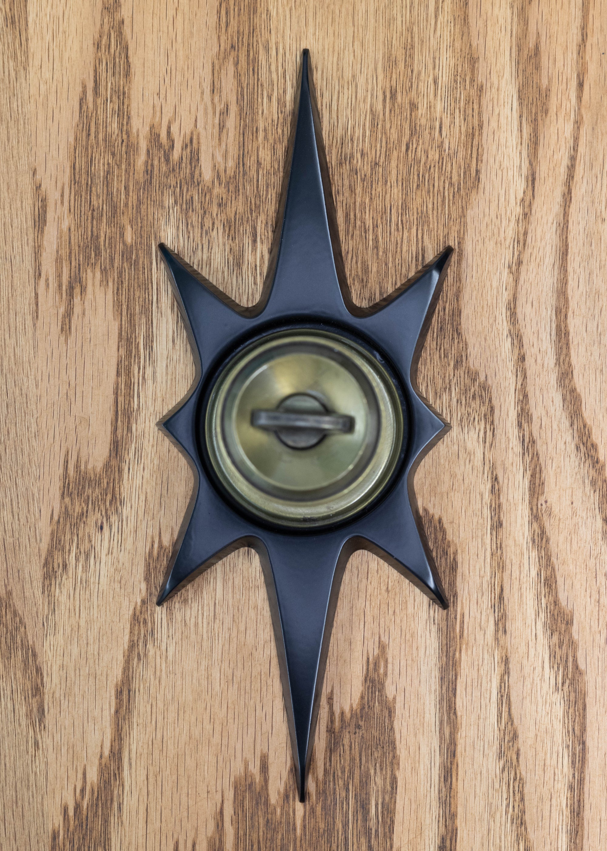 The matte black staburst escutcheon featuring a bronze doorknob.