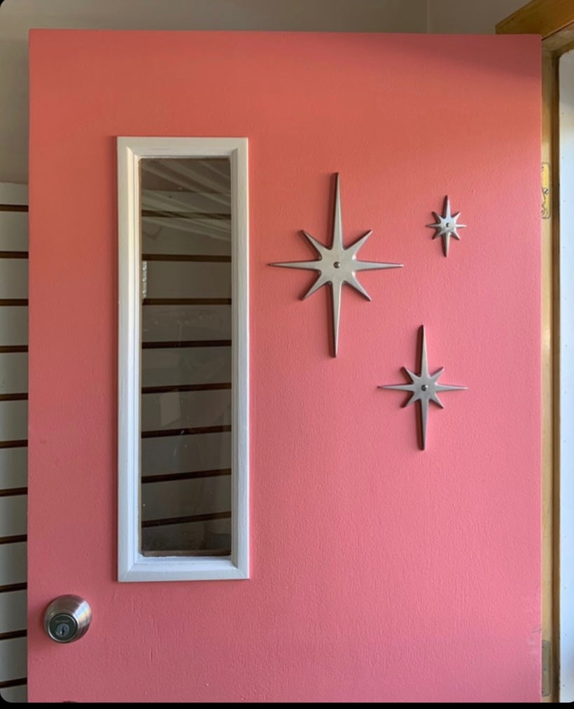 A customer photo with the set of 3 starbursts (without the peephole) on their pink door. They have them arrange with the largest star at the left, the small top right, and medium at the bottom between the two.