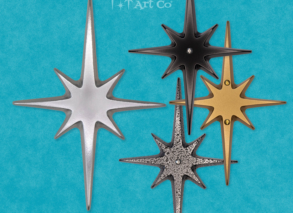 A standard toilet paper holder with two natural cast aluminum starbursts wear it attaches to the wall. They are silver with a metallic shine, and the hardware is chrome.