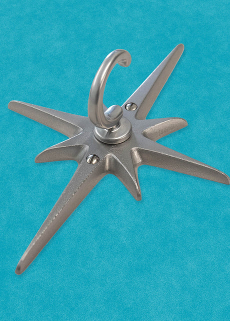 A standard toilet paper holder with two natural cast aluminum starbursts wear it attaches to the wall. They are silver with a metallic shine, and the hardware is chrome.