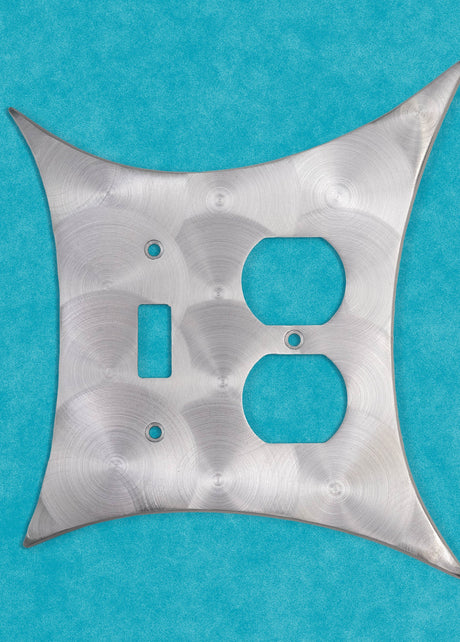 A standard toilet paper holder with two natural cast aluminum starbursts wear it attaches to the wall. They are silver with a metallic shine, and the hardware is chrome.