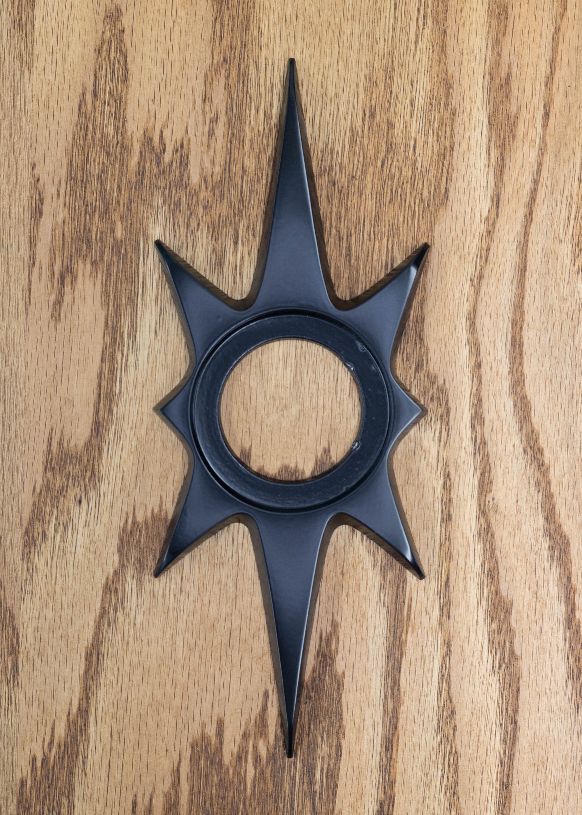 The matte black starburst dooknob escutcheon. It has an inset open circle in the center where the doorknob sits and attaches to the door. The black powder coating is a nice satin finish with slight smooth reflection of light, but is not glossy.