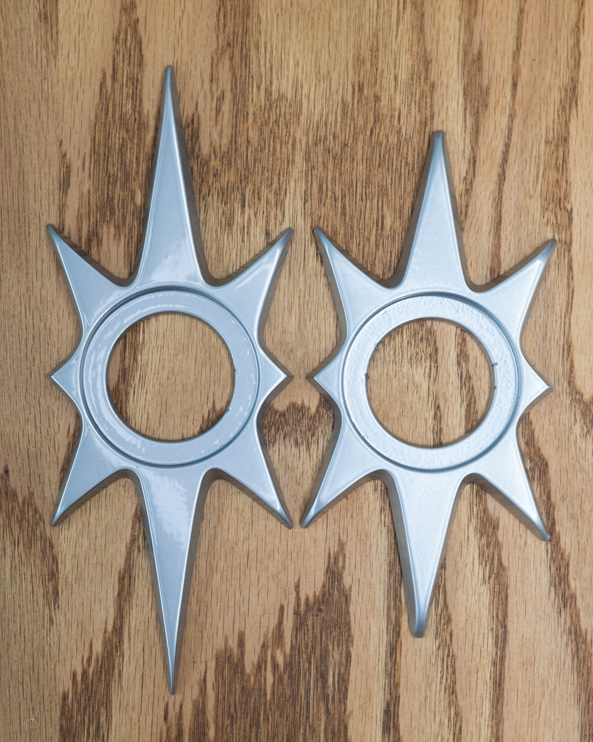 Both the 10 inch and 8 inch starburst doorknob escutcheons next to each other for a size comparison. The only difference is the length of the long points on the top and bottom.