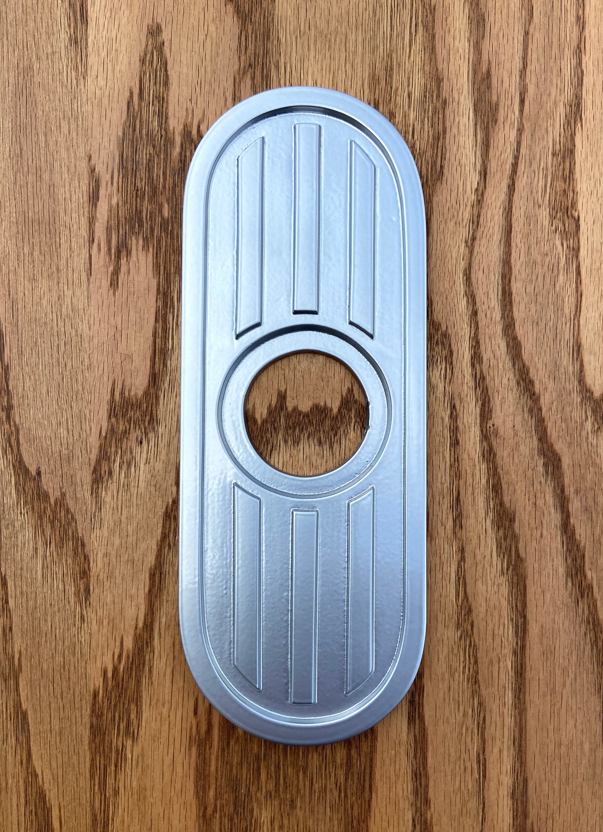 Silver powder coated escutcheon. The silver powder coating is very smooth witha bit of gloss to it. It is a light metallic silver color that shines in the light.