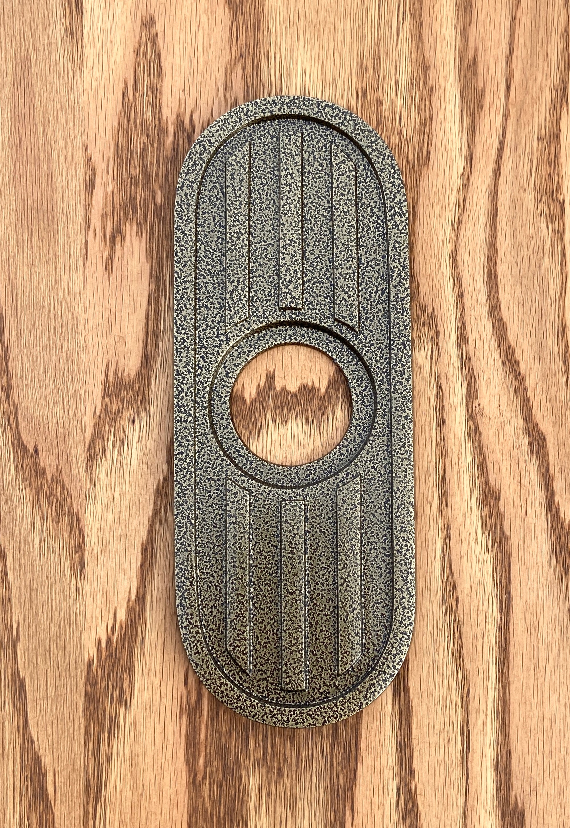 Gold vein powder coated escutcheon. The gold vein powder coat is a speckled or crackled texture mixing both gold and black. It is still smooth and slightly glossy to reflect the light.