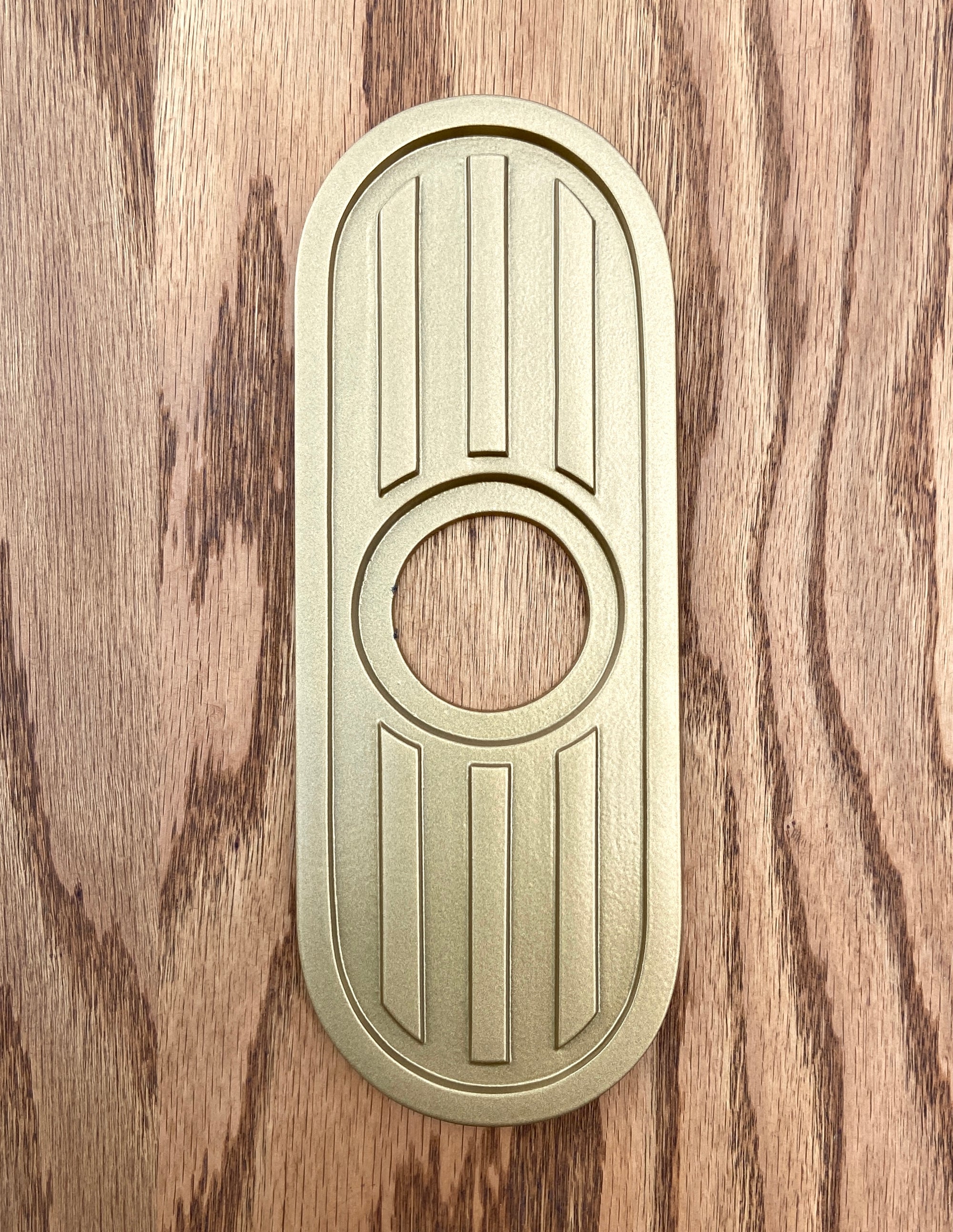 Gold powder coated escutcheon. The entire piece is gold. The surface is very smooth and has a metallic shine that reflects the light.