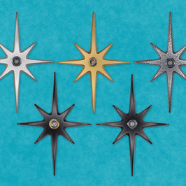 A group photo of all 5 variations of the product: a large starburst with a peephole in the center. The colors are silver, gold, black, and black frost.