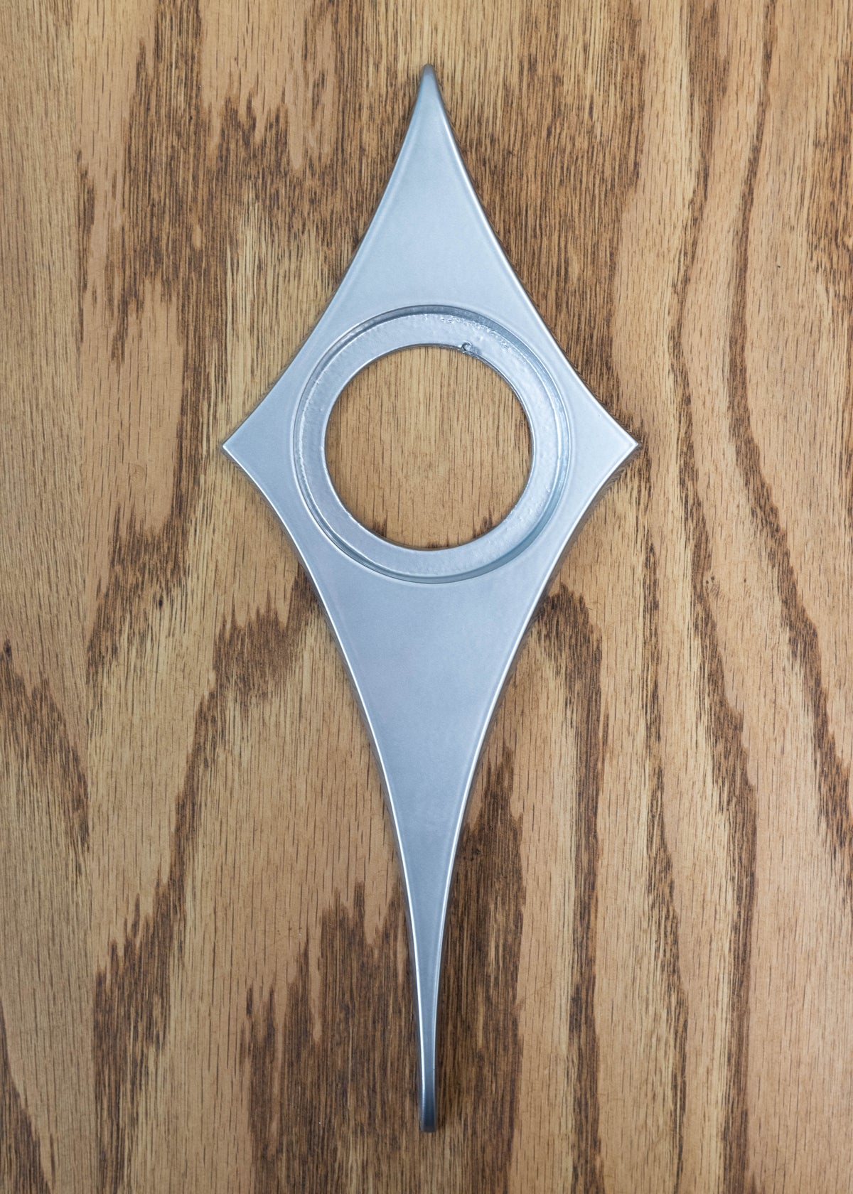The silver powder coated comet doorknob escutcheon. The surface is very smooth and has a glossy metallic finish. It is a light silver.