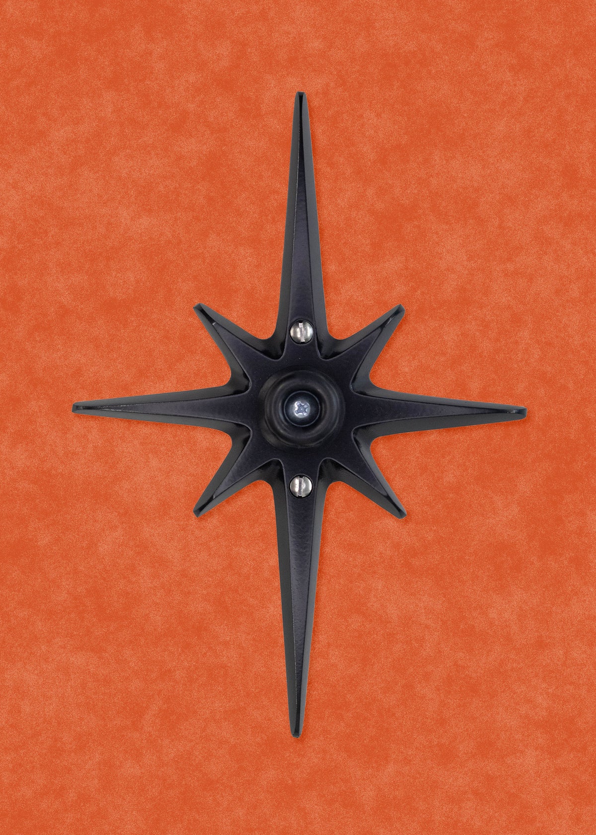 A black powder coated cast aluminum starburst with a black rubber door stop in the center. There are 3 silver screws, one in the center that attaches the the rubber stopper to the star, then one above and below the stopper that you use to attach the starburst to the wall.  the black powder coating is matte, so it isn't glossy with shine, but still has a smooth surface that can reflect some light.