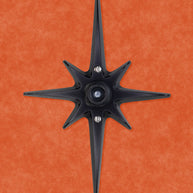A black powder coated cast aluminum starburst with a black rubber door stop in the center. There are 3 silver screws, one in the center that attaches the the rubber stopper to the star, then one above and below the stopper that you use to attach the starburst to the wall.  the black powder coating is matte, so it isn't glossy with shine, but still has a smooth surface that can reflect some light.