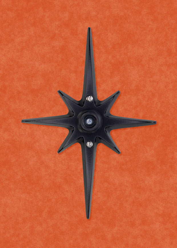 A black powder coated cast aluminum starburst with a black rubber door stop in the center. There are 3 silver screws, one in the center that attaches the the rubber stopper to the star, then one above and below the stopper that you use to attach the starburst to the wall.  the black powder coating is matte, so it isn't glossy with shine, but still has a smooth surface that can reflect some light.