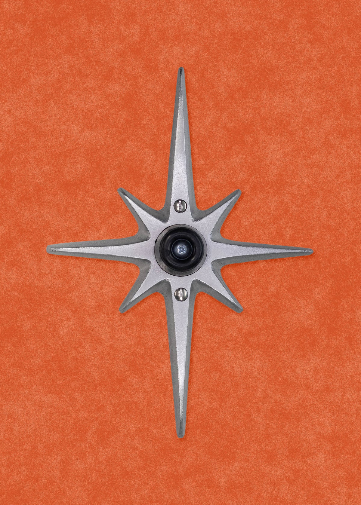 A cast aluminum starburst with a black rubber door stopper in the center. There are three screws: one in the center attaching the rubber stopper to the starburst, and one above and below the stopper for you to attach the starburst to the wall. There is no powder coating, this one is the natural aluminum which is silver in color with a bit of metallic shine to it.