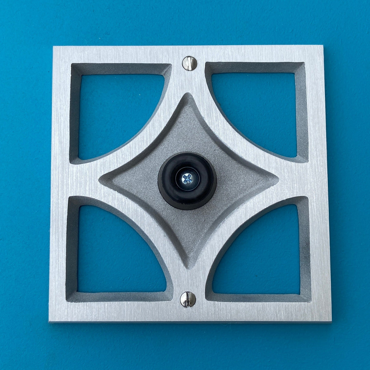 Handcrafted Breeze Block doorstop in cast aluminum with brushed finish, geometric design, and soft rubber wall-protecting stopper.